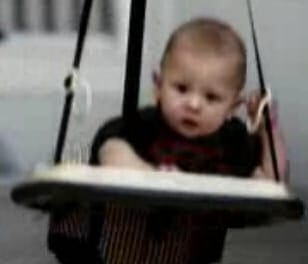 Little boy bouncing in baby grower